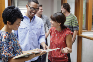 Friends looking at brochure --- Image by © Laura Doss/Corbis