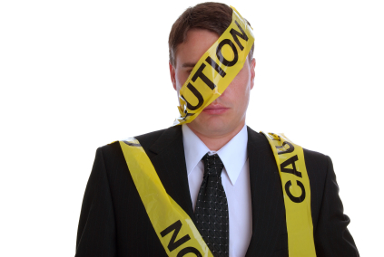 Man dressed in a business suit with caution tape wrapped around him.  Studio isolated on white.